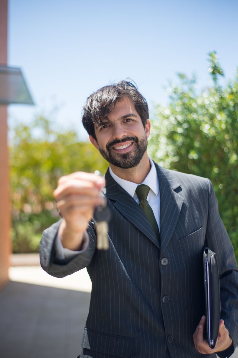 Smiling real estate agent presenting a house key outdoors