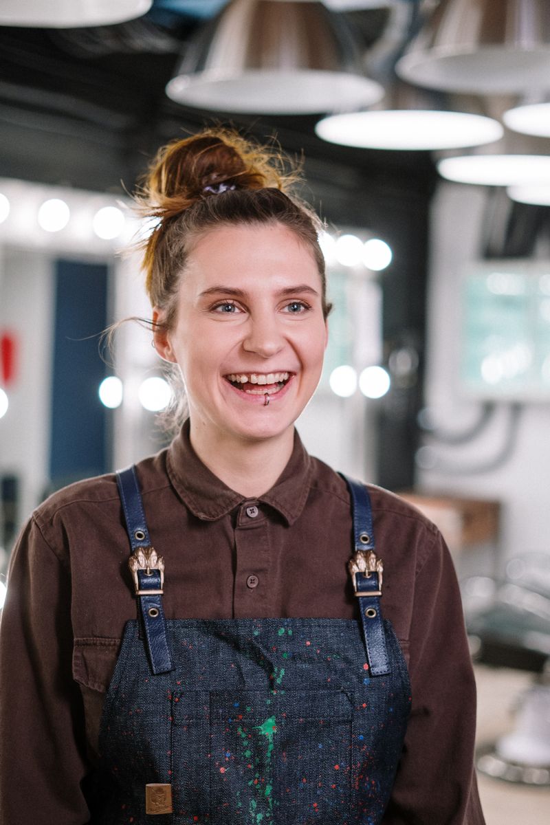 Smiling stylist in a denim apron in a modern salon